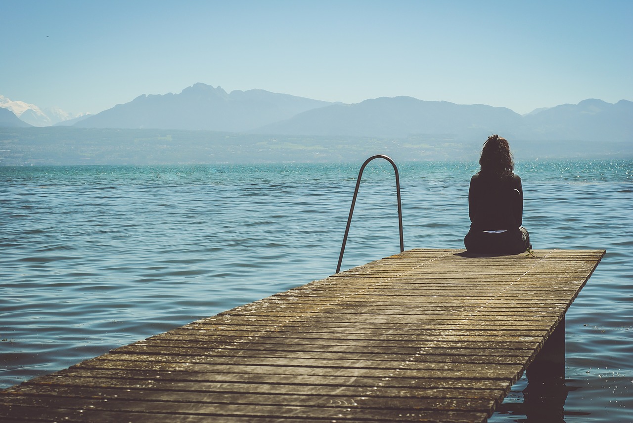 одинокая девушка на озере смотри на горы